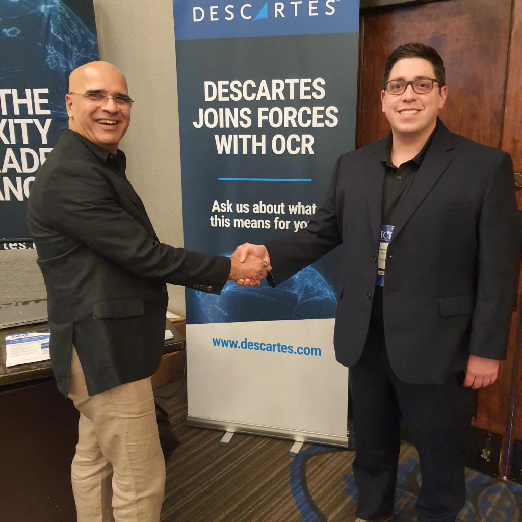 Deux experts en conformité des exportations de Descartes à la conférence ITAR 2024 de l'ICPA devant un panneau indiquant "Descartes s'associe à l'OCR".